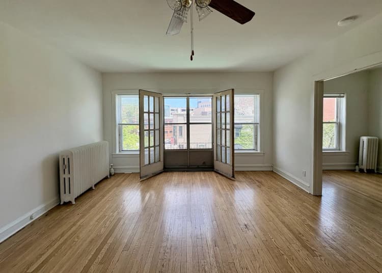 Milwaukee County apartments for rent - image - Bright and airy living space with wooden floors, large windows, and elegant French doors offering a charming view of the neighborhood.