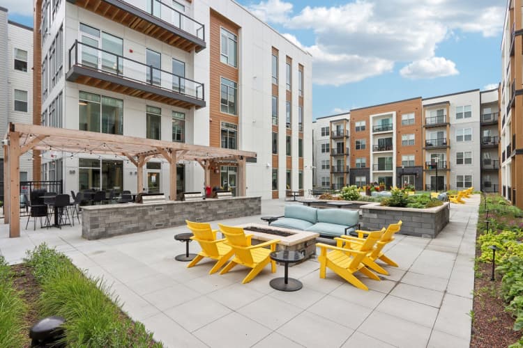 Milwaukee County apartments for rent - image - A patio with yellow chairs and tables is surrounded by apartment buildings