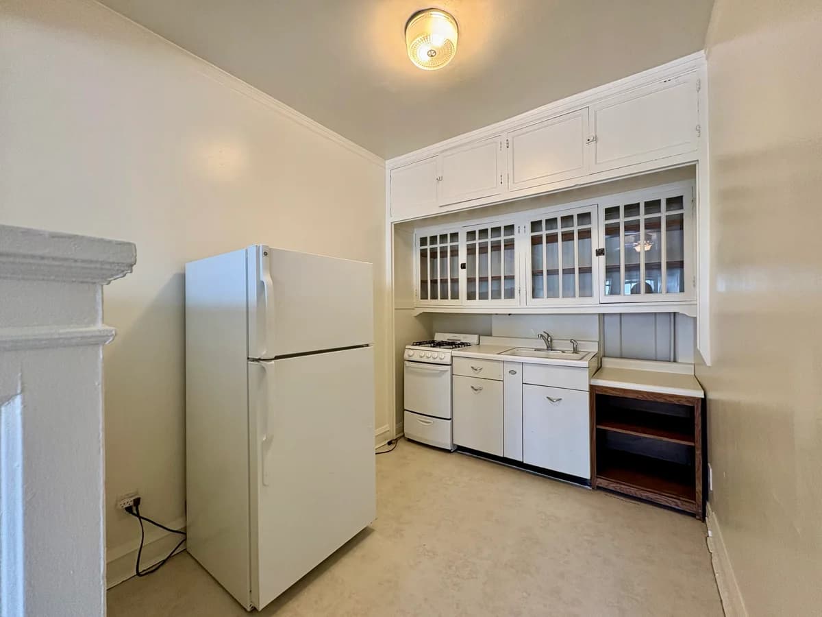 Milwaukee County apartments for rent - image - Charming vintage kitchen featuring classic white cabinetry, a spacious fridge, and cozy lighting.
