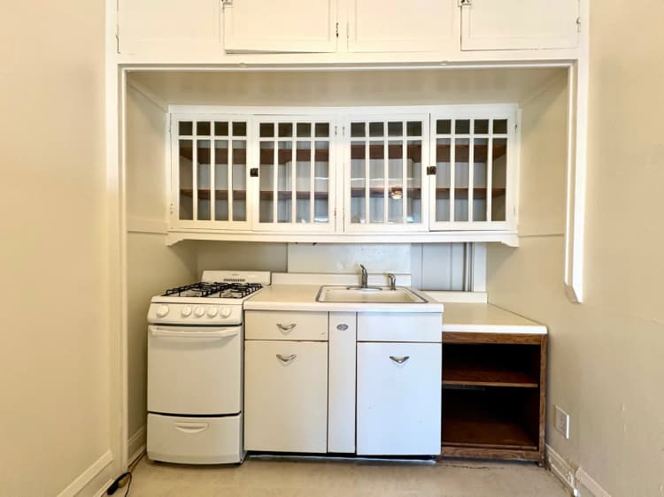 Milwaukee County apartments for rent - image - Charming vintage kitchen with built-in shelving, gas stove, and classic white cabinetry.