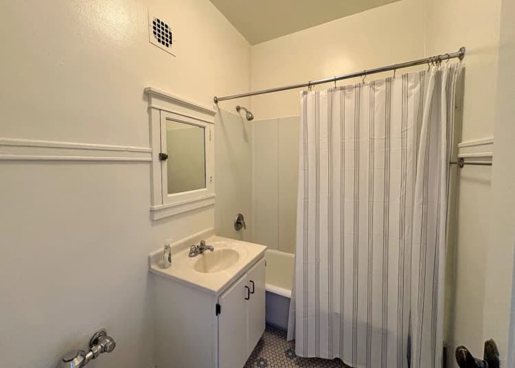 Milwaukee County apartments for rent - image - Bright and clean bathroom with classic white fixtures, featuring a mirrored vanity, shower, and elegant tile flooring.