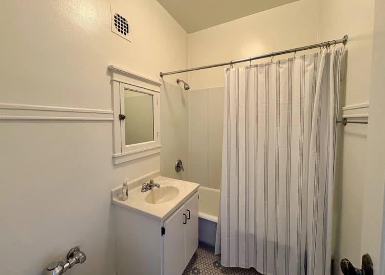 Milwaukee County apartments for rent - image - Bright and clean bathroom with classic white fixtures, featuring a mirrored vanity, shower, and elegant tile flooring.