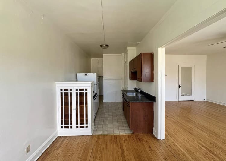 Milwaukee County apartments for rent - image - Charming apartment with a compact kitchen featuring modern cabinetry, adjacent to a spacious, light-filled living area with hardwood flooring.